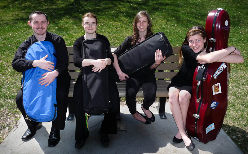 Magic City Strings sitting on bench in Pioneer Park